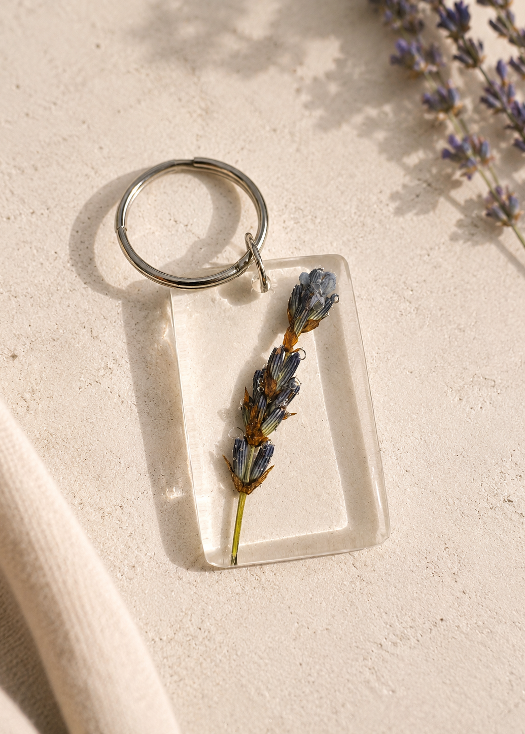 Keychain with dried lavender inside a clear rectangular frame on a light surface.