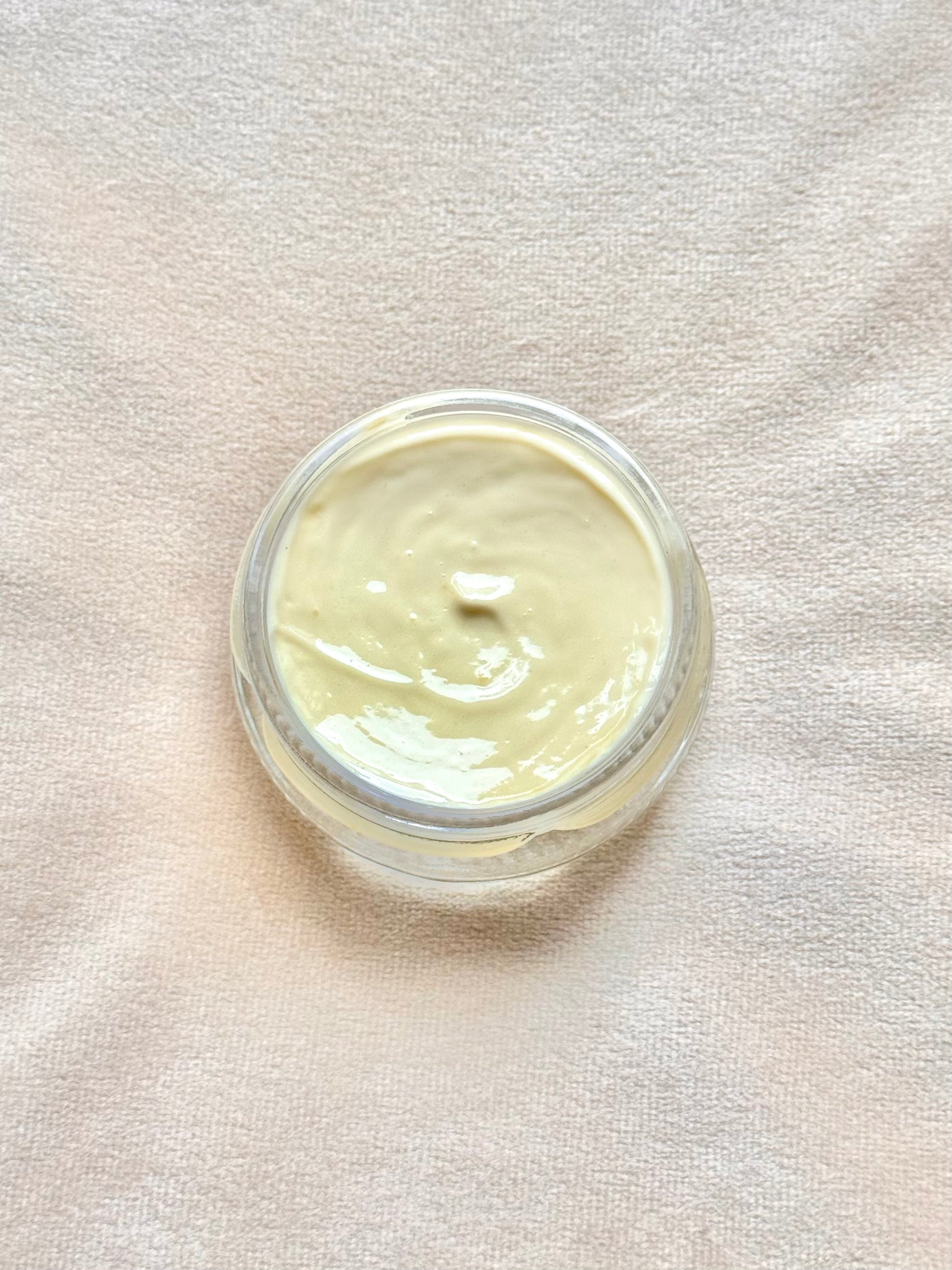 Jar of cream on a textured beige surface