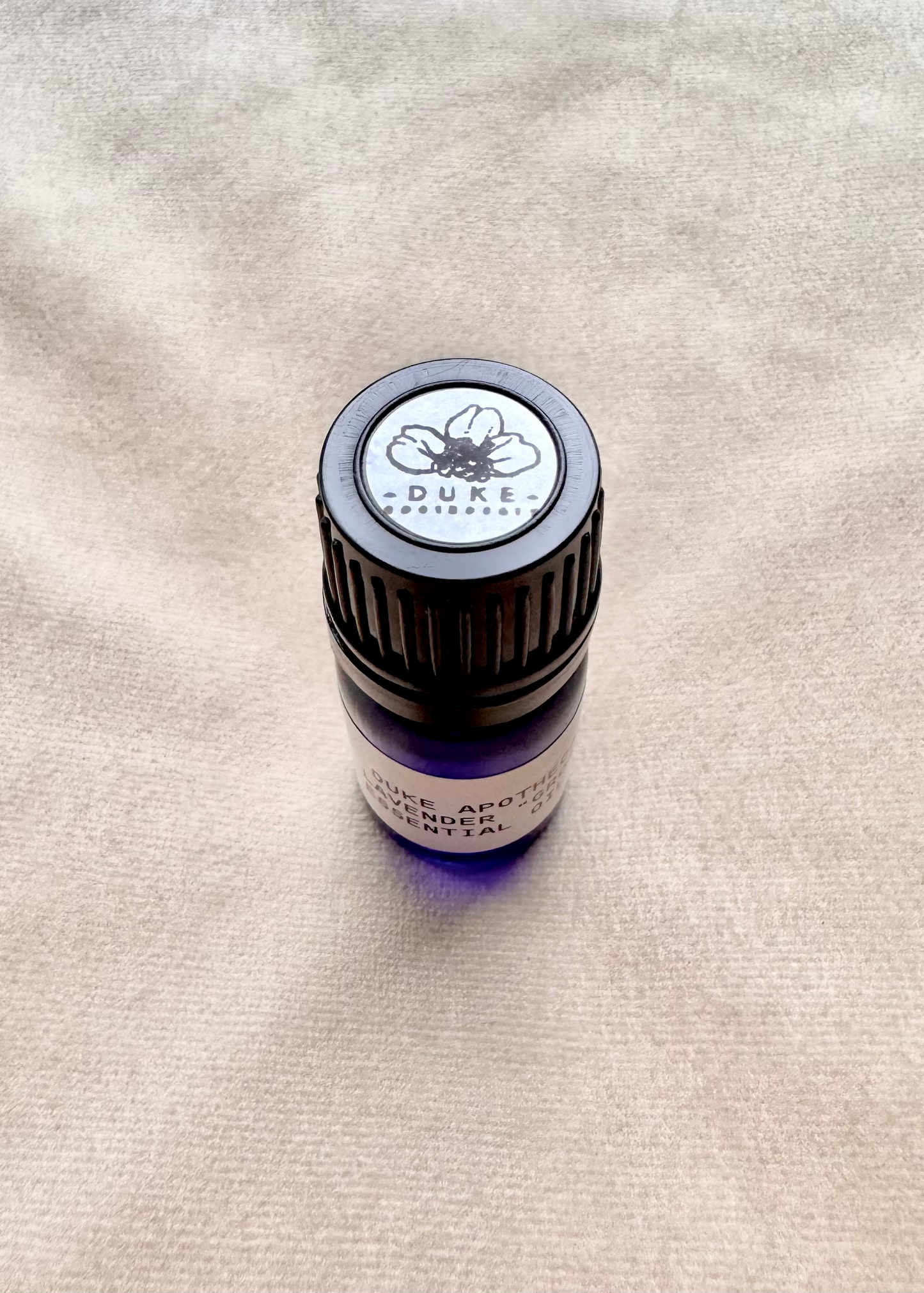 Duke Apothecary essential oil bottle on fabric beige background
