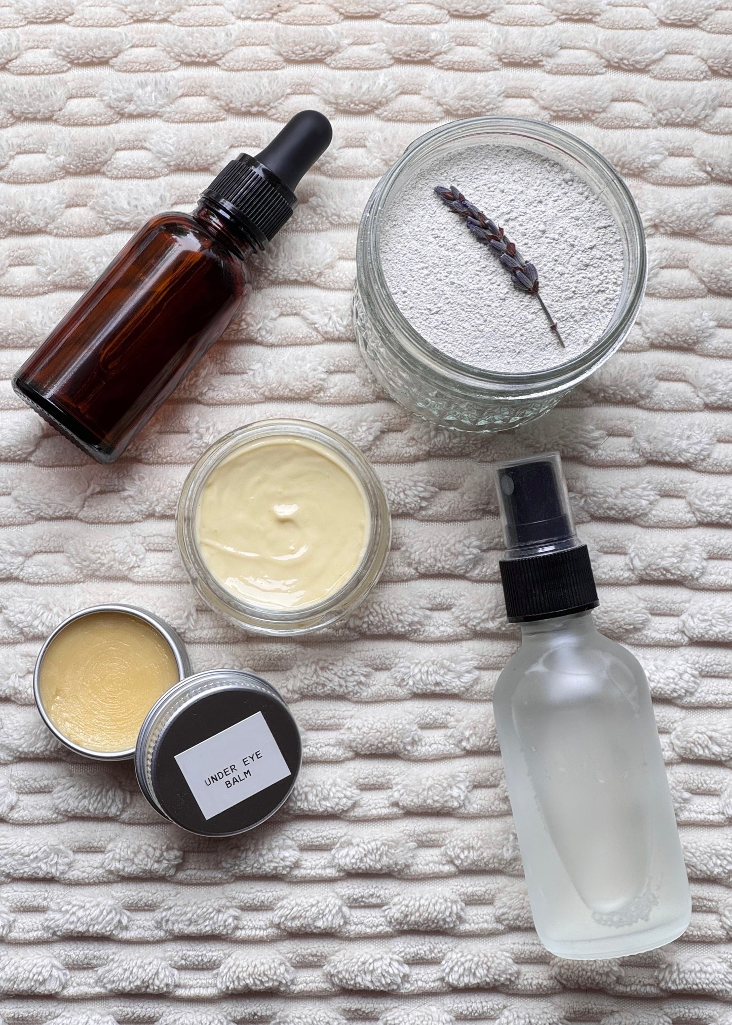 Collection of skincare products including a bottle, jar, and cream on a textured surface