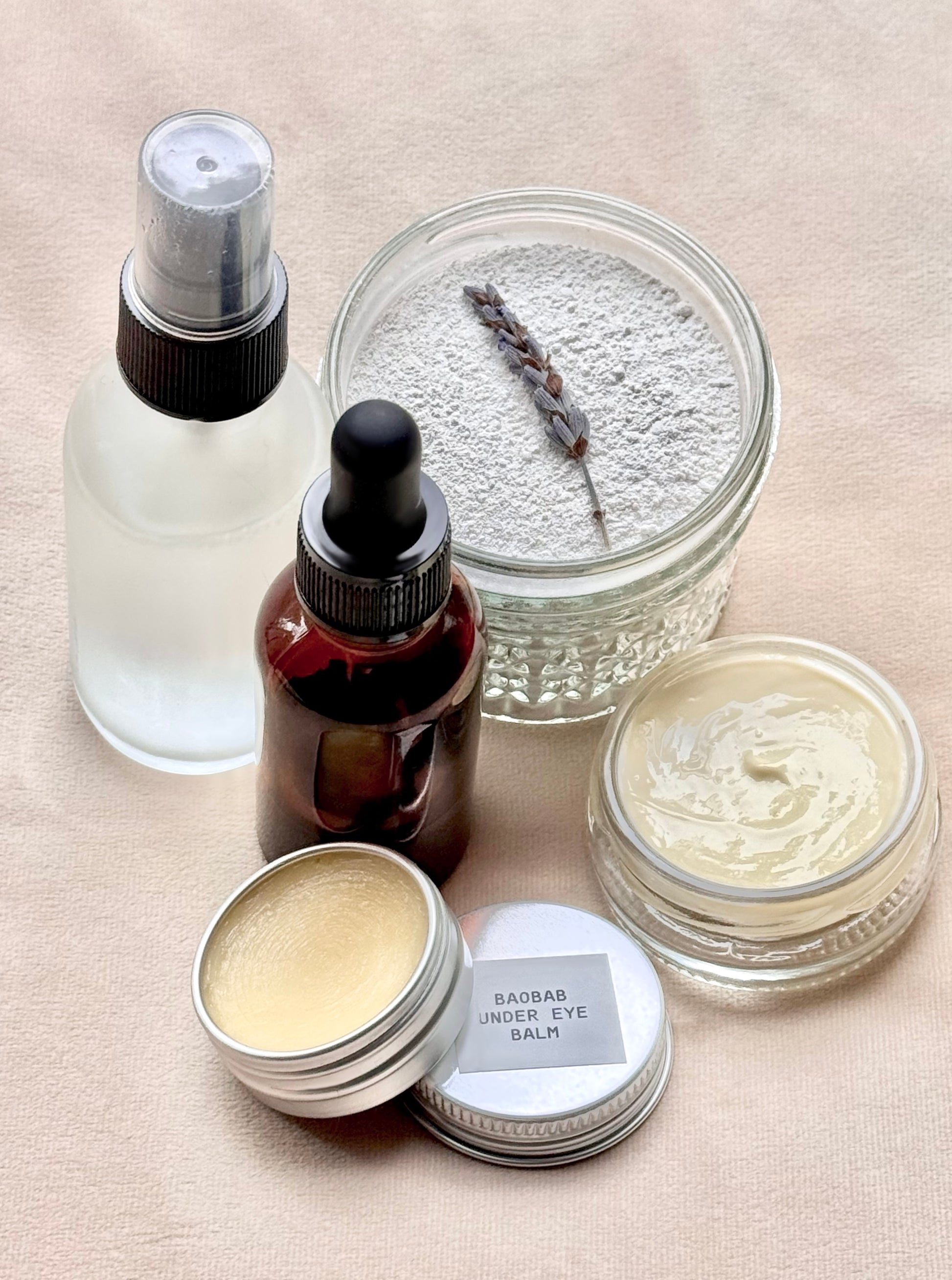 Collection of skincare products including jars, bottles, and a spray bottle on a beige surface.