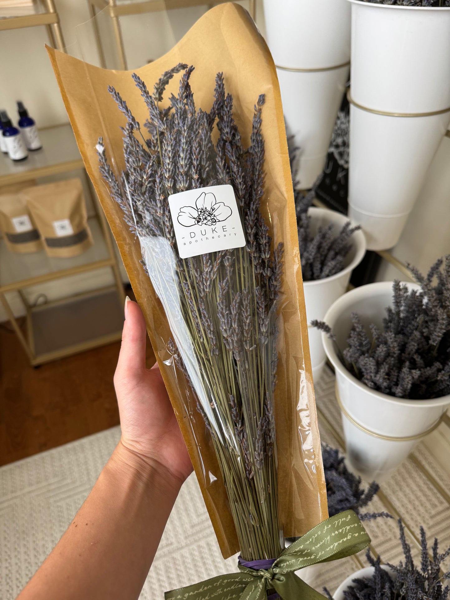 Bouquet of lavender wrapped in brown paper with a visible brand label, held by a person.