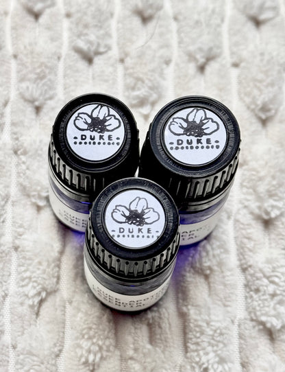 Three Duke Apothecary essential oil bottles on a textured white surface