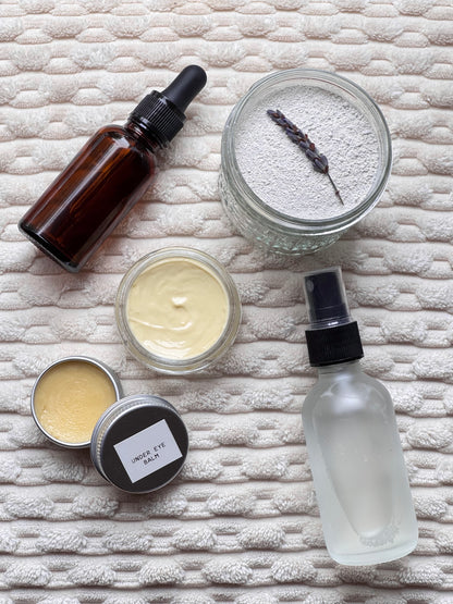 Collection of skincare products including a bottle, jar, and cream on a textured surface
