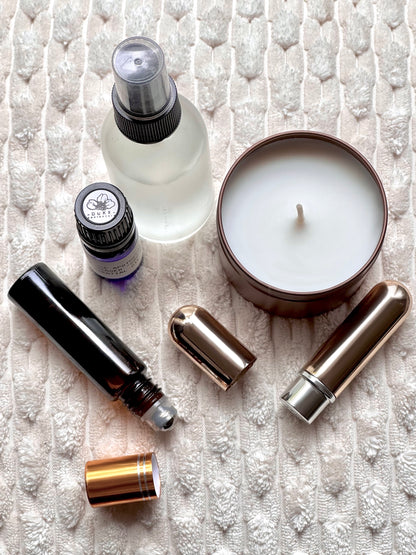 Collection of skincare and wellness products including a candle, bottles, and roller balls on a textured white surface.