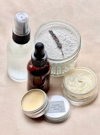 Collection of skincare products including jars, bottles, and a spray bottle on a beige surface.