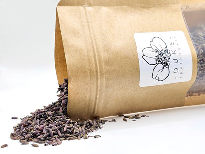 Open brown paper bag with lavender seeds spilling out, featuring a Duke & Company label.