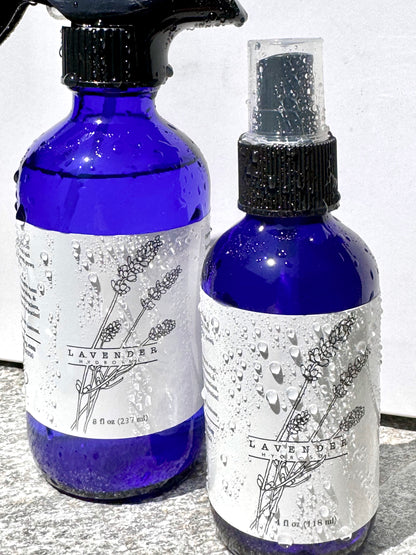 Two blue spray bottles with lavender-themed labels on a light background